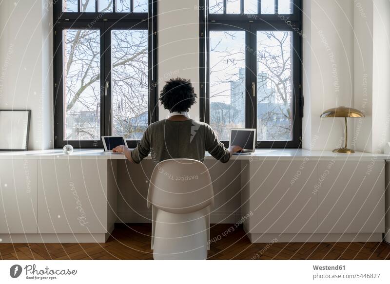 Mann arbeitet zu Hause vor dem Panoramafenster mit Laptop und Tablett Notebook Laptops Notebooks Tablet Computer Tablet-PC Tablet PC iPad Tablet-Computer Männer