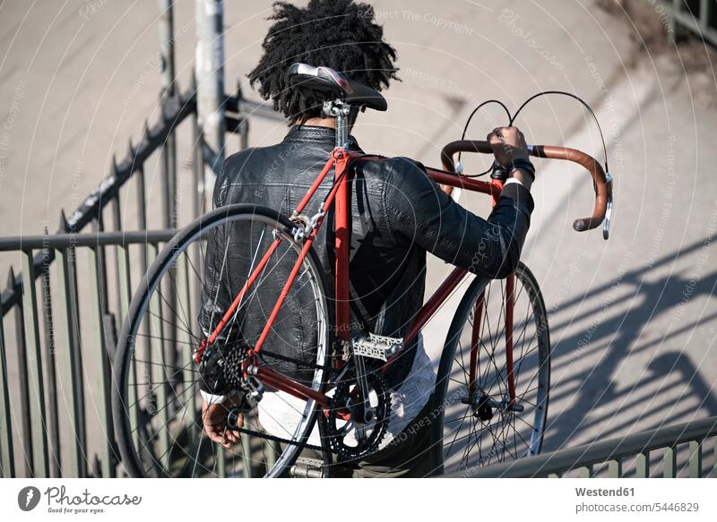 Mann trägt sein Fahrrad die Treppe hinunter tragen transportieren Männer männlich Bikes Fahrräder Räder Rad Erwachsener erwachsen Mensch Menschen Leute People