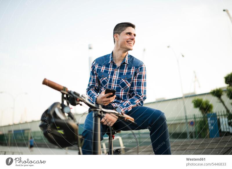 Glücklicher junger Mann mit Fahrrad und Handy Männer männlich Bikes Fahrräder Räder Rad lachen Mobiltelefon Handies Handys Mobiltelefone Erwachsener erwachsen
