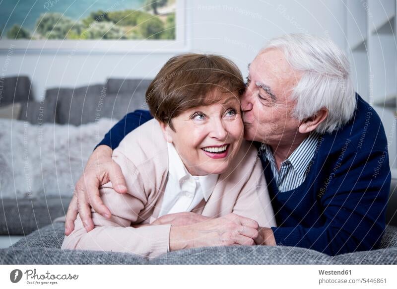 Älteres Paar liegt auf der Couch, umarmt und küsst sich Sofa Couches Liege Sofas küssen Küsse Kuss umarmen Umarmung Umarmungen Arm umlegen Pärchen Paare
