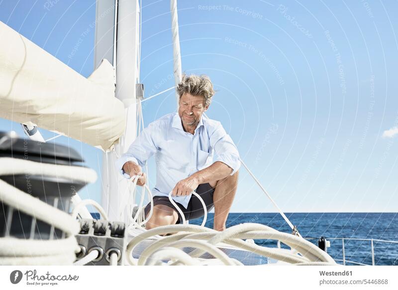 Älterer Mann arbeitet mit Seilen auf einem Segelboot Männer männlich Segeln segelnd segelt Erwachsener erwachsen Mensch Menschen Leute People Personen Bootsport
