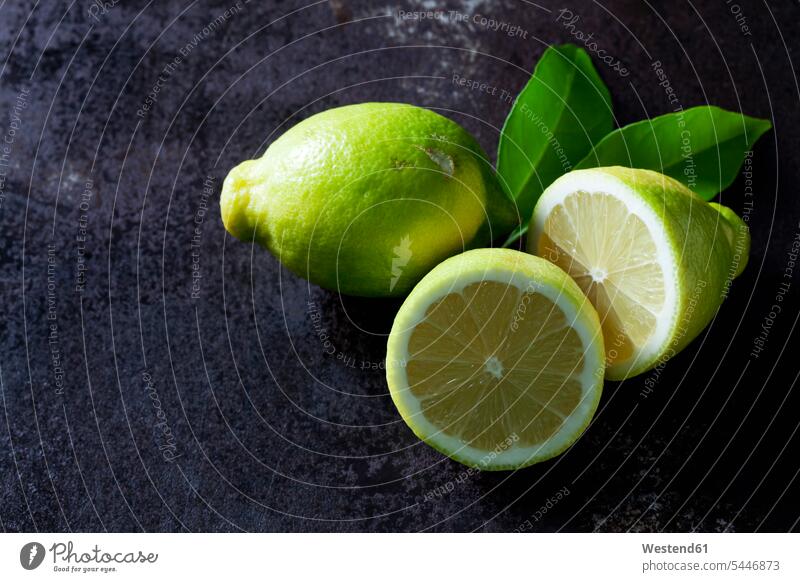 Grüne Bio-Zitronen auf dunklem Hintergrund Textfreiraum Erhöhte Ansicht Erhöhte Ansichten Gesunde Ernährung Ernaehrung Gesunde Ernaehrung Gesundheit gesund
