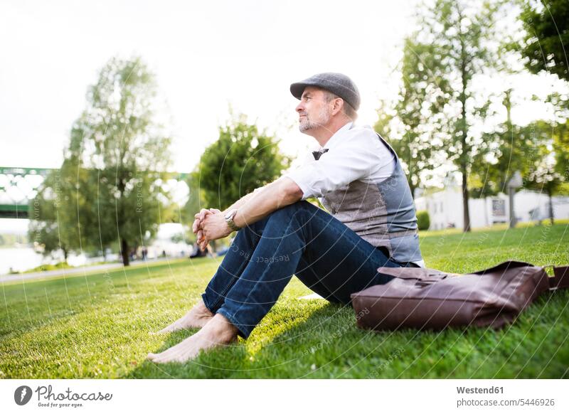 Reifer Geschäftsmann im Stadtpark auf Rasen sitzend entspannt entspanntheit relaxt Mann Männer männlich sitzt Pause Wiese Wiesen Entspannung relaxen entspannen