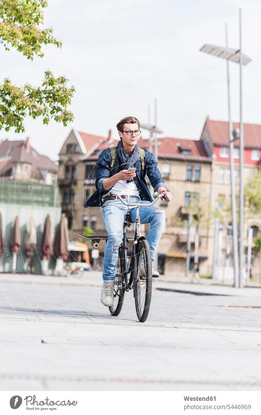 Junger Mann mit Fahrrad in der Stadt mit Handy Männer männlich fahren Mobiltelefon Handies Handys Mobiltelefone Bikes Fahrräder Räder Rad Erwachsener erwachsen
