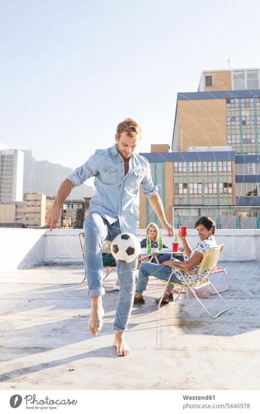 Freunde treffen sich im Sommer auf der Dachterrasse und spielen Fussball Gemütlich Wohlfühlen behaglich Gemütlichkeit Freizeitkleidung casual Freizeitbekleidung