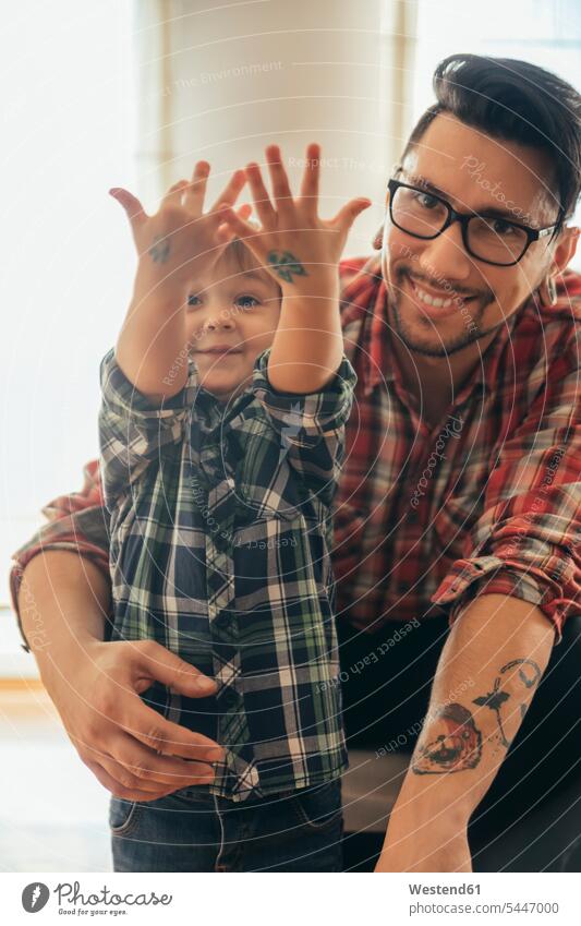 Stolzer Sohn zeigt gemalte Tätowierungen auf seinen Händen Söhne Vater Papas Väter Vati Vatis Papis Tattoo Tatoos Taetowierung Tattoos Taetowierungen lächeln