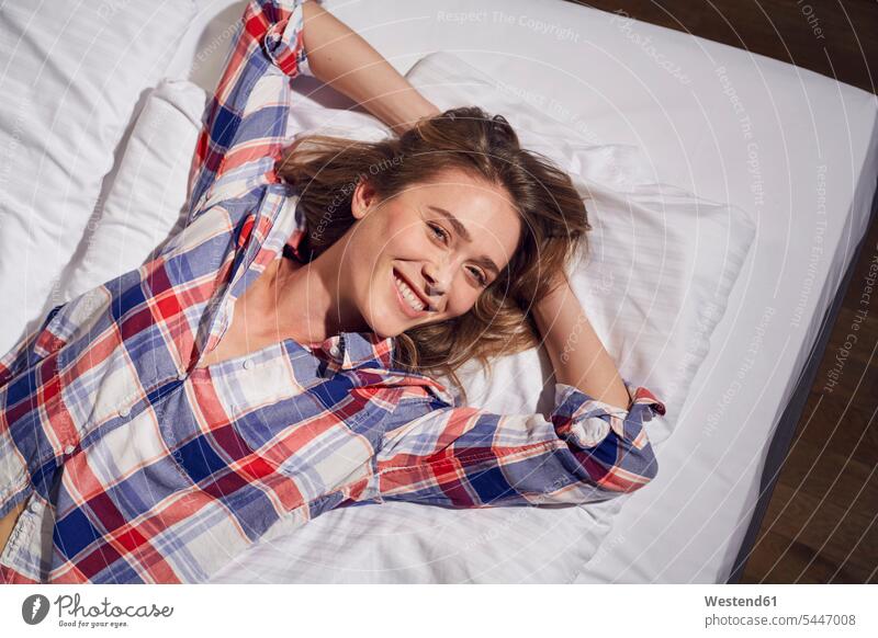 Porträt einer lachenden Frau auf dem Bett liegend mit Händen hinter dem Kopf Betten weiblich Frauen Portrait Porträts Portraits Erwachsener erwachsen Mensch