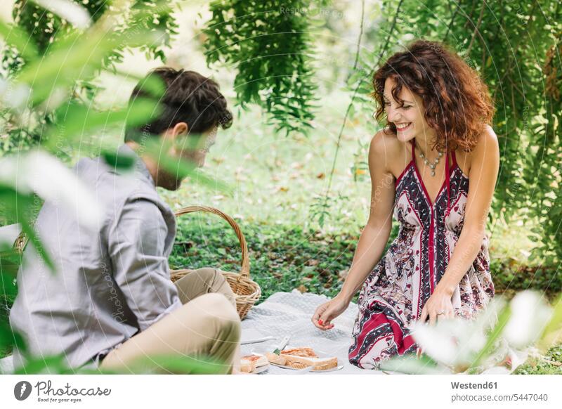 Glückliches Paar beim Picknick im Park lächeln Pärchen Paare Partnerschaft picknicken Parkanlagen Parks Mensch Menschen Leute People Personen Mahlzeit