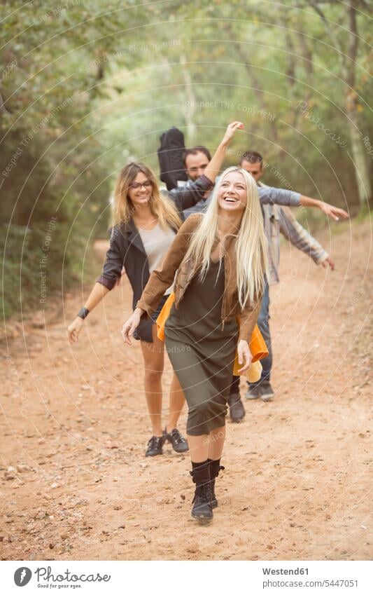 Vier glückliche Freunde amüsieren sich auf Waldwegen gehen gehend geht Forst Wälder Glück glücklich sein glücklichsein Freundschaft Kameradschaft Gemeinschaft