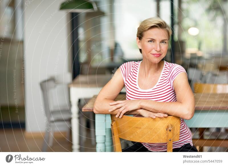 Porträt einer selbstbewussten blonden Frau, die auf einem Stuhl sitzt lächeln Geschäftsfrau Geschäftsfrauen Businesswomen Businessfrauen Businesswoman weiblich