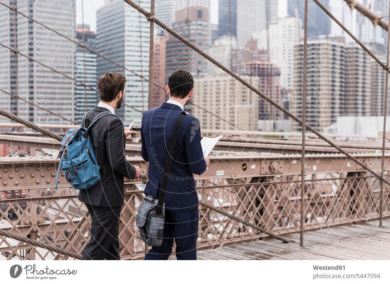 USA, New York City, zwei Geschäftsleute auf der Brooklyn Bridge sprechen reden Brücke Bruecken Brücken New York State Geschäftsmann Businessmann Businessmänner