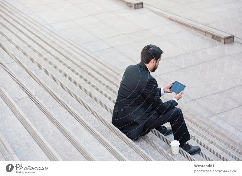 Geschäftsmann sitzt auf der Treppe mit Tablette und Kaffee zum Mitnehmen Pause Tablet Computer Tablet-PC Tablet PC iPad Tablet-Computer Businessmann