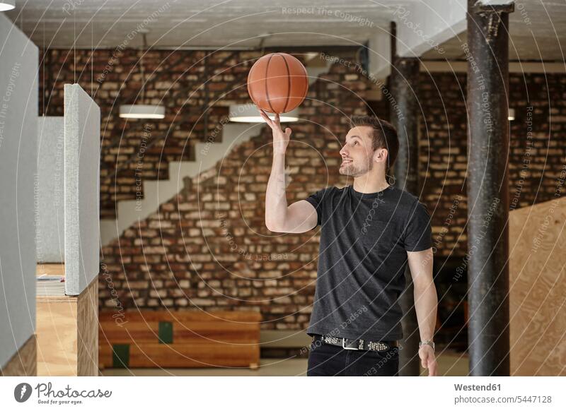 Junger Mann im Amt spielt mit Basketball Können Fähigkeit Fertigkeit Könnerschaft lächeln Work-Life-Balance Ball Bälle Büro Office Büros Jungunternehmer