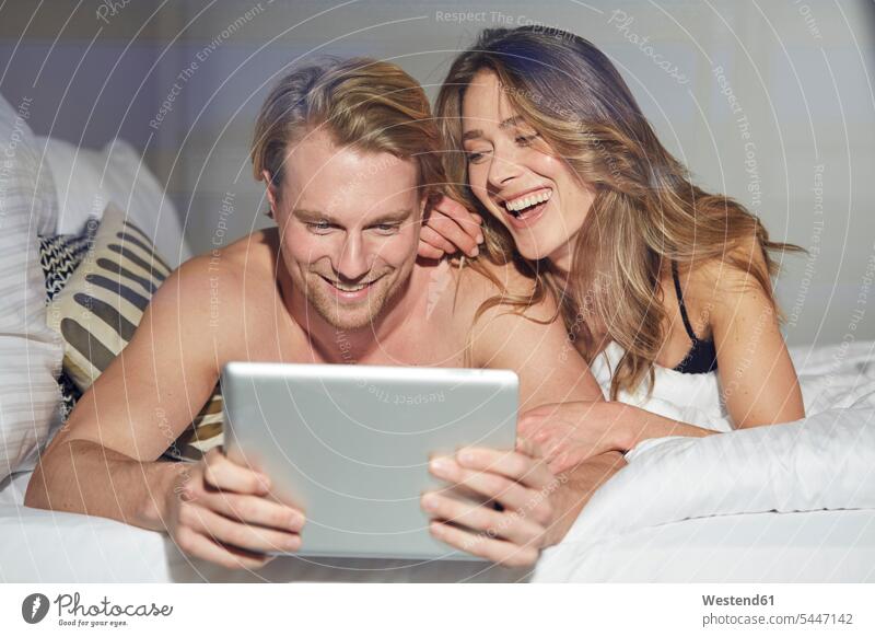 Porträt eines entspannten Paares mit auf dem Bett liegendem Tablett Portrait Porträts Portraits Tablet Computer Tablet-PC Tablet PC iPad Tablet-Computer Pärchen