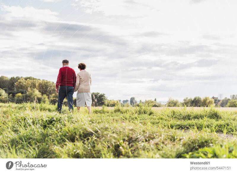 Älteres Ehepaar bei einem Spaziergang in ländlicher Landschaft Paar Pärchen Paare Partnerschaft Senior ältere Männer älterer Mann Senioren gehen gehend geht