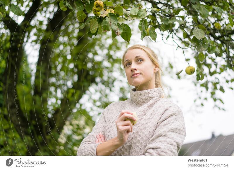Porträt einer jungen Frau am Apfelbaum im Garten weiblich Frauen Äpfel Aepfel Portrait Porträts Portraits Apfelbäume Apfelbaeume Malus domestica Gärten Gaerten