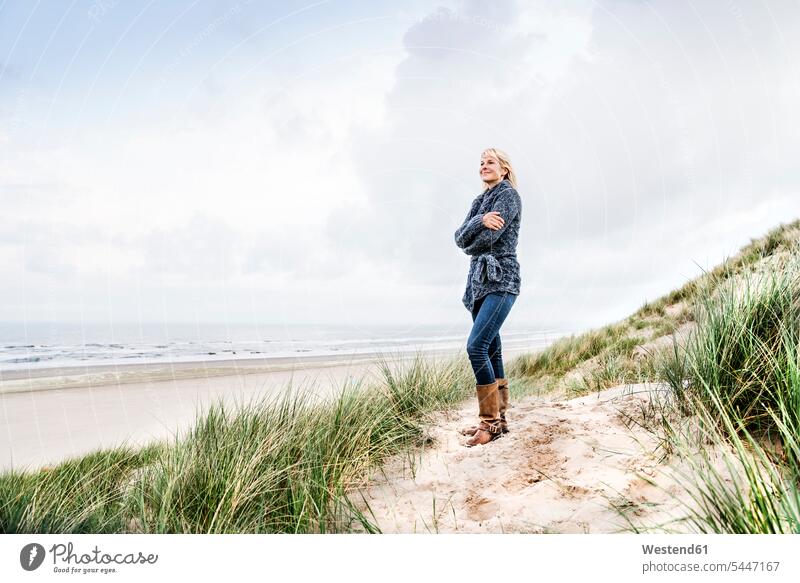 Lächelnde Frau steht in den Dünen Sanddüne Sanddünen lächeln stehen stehend weiblich Frauen Strand Beach Straende Strände Beaches Duenen Erwachsener erwachsen