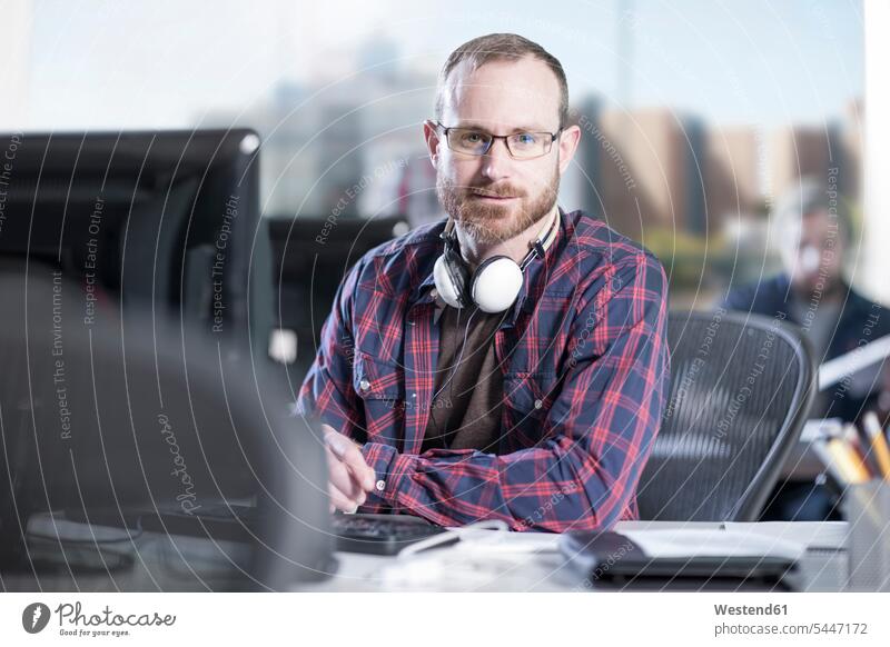 Porträt eines selbstbewussten Mannes am Schreibtisch im Büro Office Büros Arbeitsplatz Arbeitsstätte Arbeitstelle Business Geschäftsleben Geschäftswelt