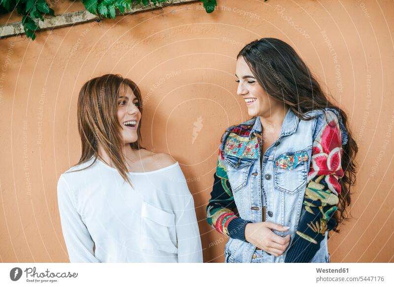 Zwei lachende Freunde vor der Mauer Freundinnen Mauern Freundschaft Kameradschaft Wand Wände Waende positiv Emotion Gefühl Empfindung Emotionen Gefühle fühlen