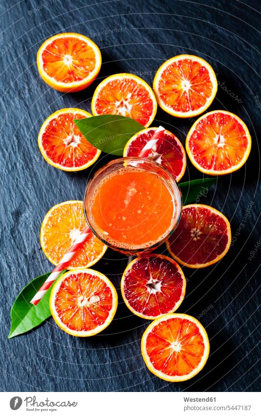 Geschnittene Blutorangen und Glas Orangensaft auf Schiefer Food and Drink Lebensmittel Essen und Trinken Nahrungsmittel Citrus sinensis Apfelsinen Variation