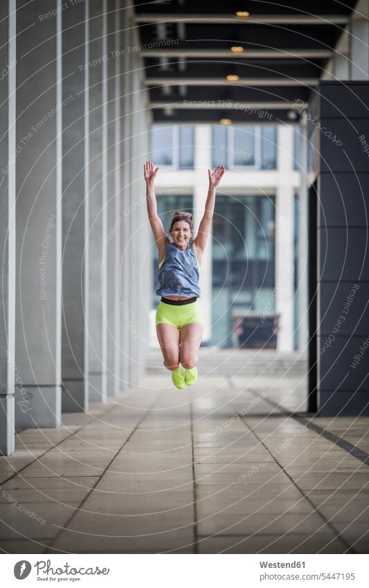 Sportliche Frau springt in Spielhalle glücklich Glück glücklich sein glücklichsein springen hüpfen Sportlerin Sportlerinnen trainieren weiblich Frauen Sprung