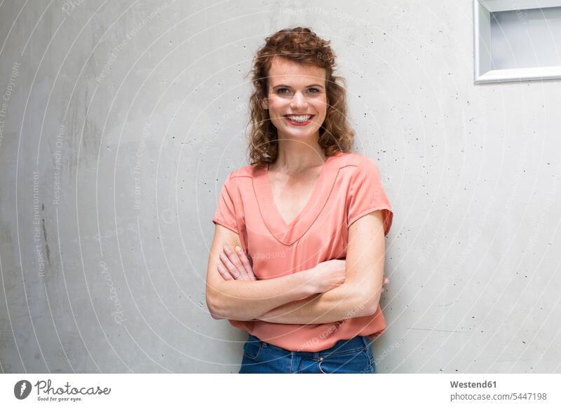 Porträt einer lächelnden Frau, die gegen eine Betonwand lehnt Betonwände Betonwaende weiblich Frauen Wand Wände Waende Erwachsener erwachsen Mensch Menschen