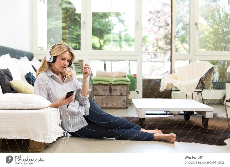 Entspannte Frau zu Hause beim Musikhören weiblich Frauen Kopfhörer Kopfhoerer entspannt entspanntheit relaxt hoeren liegen liegend liegt Erwachsener erwachsen