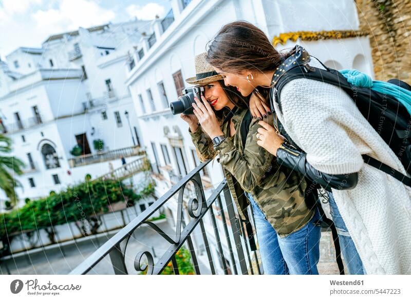 Zwei junge Frauen in einer Stadt, die mit einer Kamera fotografieren Freundinnen Fotoapparat Fotokamera lächeln Freunde Freundschaft Kameradschaft Touristin