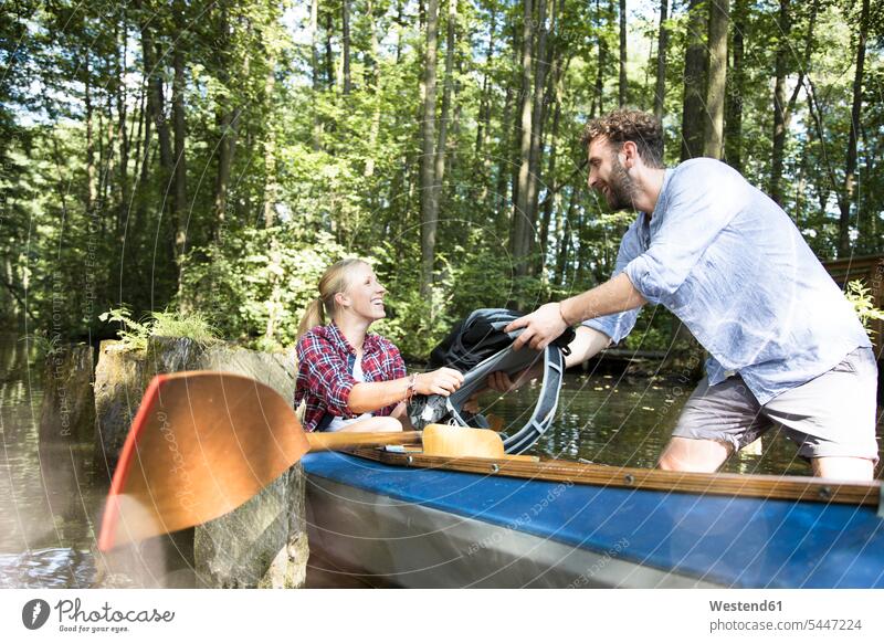 Glückliches junges Paar beim Einsteigen ins Kanu in einem Waldbach Kanus einsteigen Forst Wälder glücklich glücklich sein glücklichsein Bach Bäche Baeche