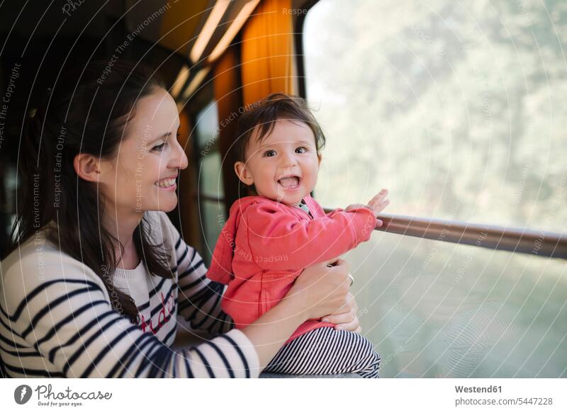 Glückliche Mutter und kleines Mädchen reisen mit dem Zug lachen Bahnen Züge Baby Babies Babys Säuglinge Kind Kinder verreisen Mami Mutti Mütter Mama positiv