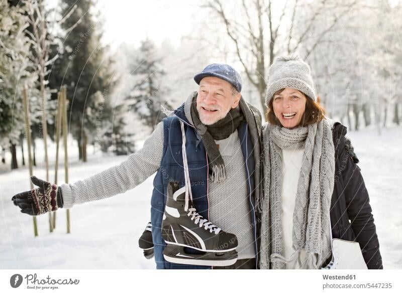 Glückliches älteres Paar mit Schlittschuhen in Winterlandschaft Pärchen Paare Partnerschaft Schlittschuhläufer Schlittschuhlaeufer Spaß Spass Späße spassig