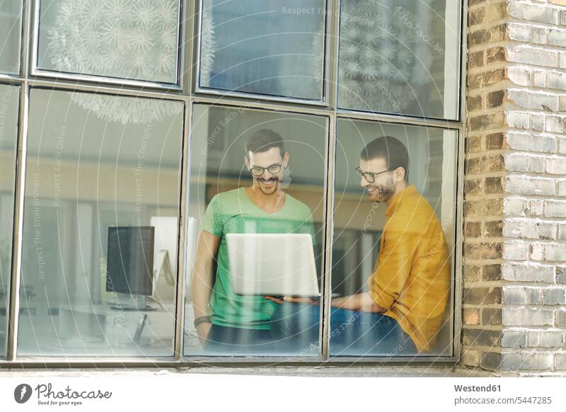 Junge Berufstätige am Fenster mit Laptop sitzen sitzend sitzt Kreative Kreativer Kreativer Beruf Laptop benutzen Laptop benützen Fensterbank Fensterbrett