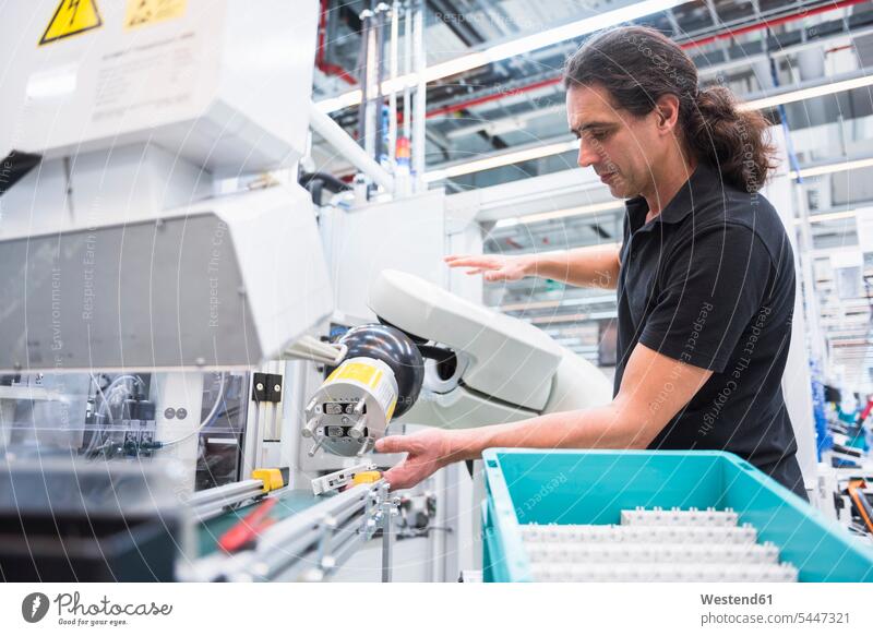 Mann bedient Montageroboter in der Fabrik arbeiten Arbeit Fabriken Männer männlich Roboter Erwachsener erwachsen Mensch Menschen Leute People Personen Industrie
