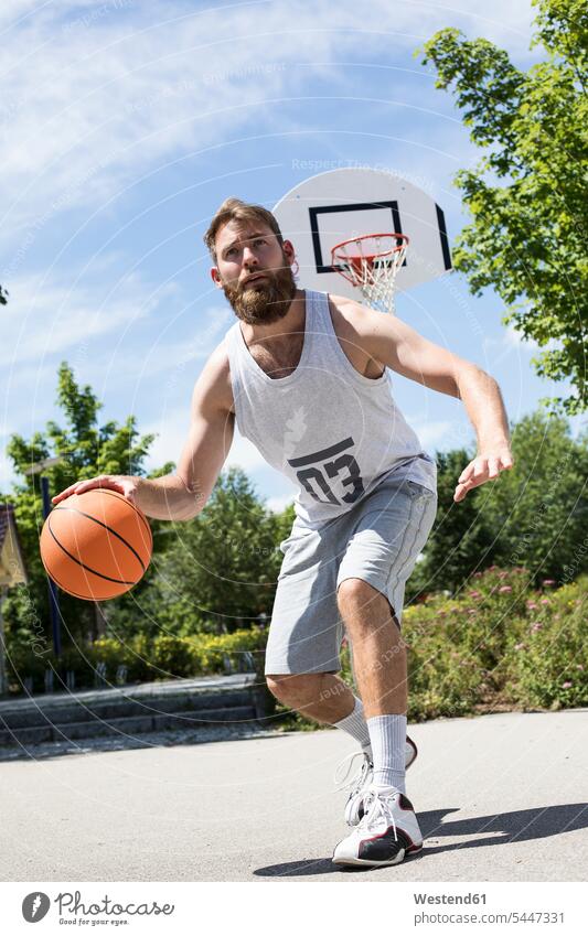 Mann spielt Basketball auf einem Aussenplatz Basketbaelle Basketbälle Männer männlich spielen trainieren Sport Erwachsener erwachsen Mensch Menschen Leute