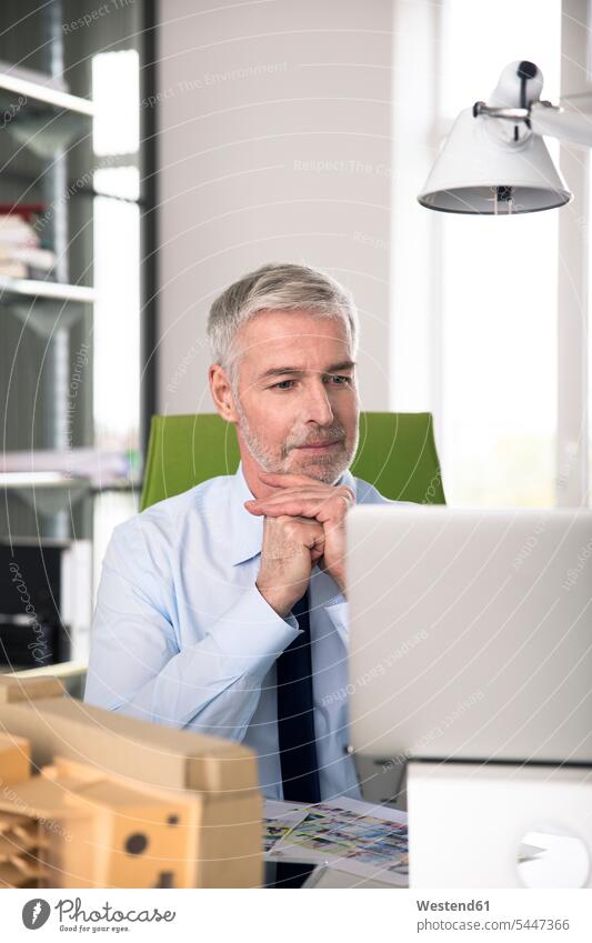 Geschäftsmann, der im Büro arbeitet und einen Laptop benutzt Kompetenz kompetent arbeiten Arbeit sitzen sitzend sitzt Konzentration konzentriert konzentrieren