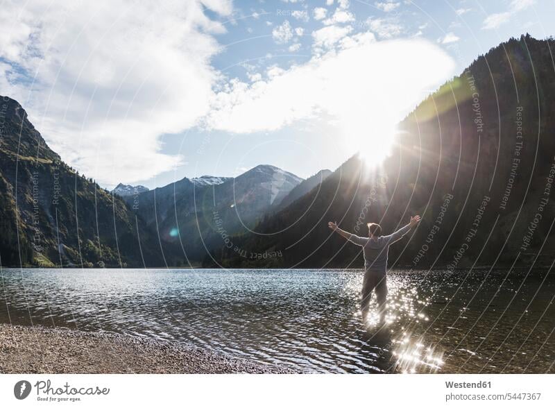 Österreich, Tirol, Wanderer steht mit ausgestreckten Armen im Bergsee Bergseen stehen stehend Mann Männer männlich See Seen wandern Wanderung Berge Gewässer