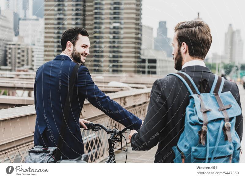 USA, New York City, zwei Geschäftsleute mit Fahrrad auf der Brooklyn Bridge sprechen reden Brücke Bruecken Brücken lächeln Geschäftsmann Businessmann