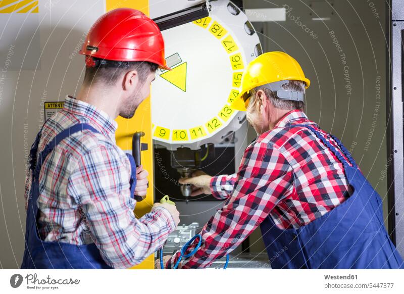 Zwei Männer in der Fabrik arbeiten an einer CNC-Maschine Industrie bedienen Business Beruf erklären Automatisierung Mittelstand Zusammenarbeit Fräse Schutz