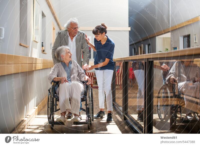 Geriatrische Krankenschwester, die älteren Männern und Frauen hilft, den Korridor hinunterzugehen Altenpflegerin Altenpflegerinnen Pflegerin Pflegerinnen