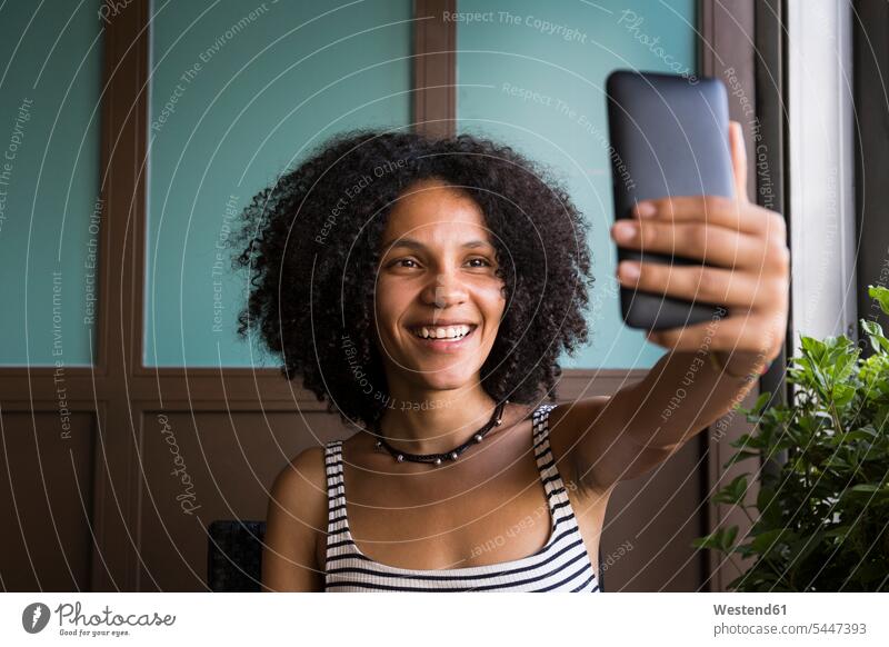 Glückliche junge Frau nimmt Selfie in einem Café Portrait Porträts Portraits Selfies weiblich Frauen Erwachsener erwachsen Mensch Menschen Leute People Personen