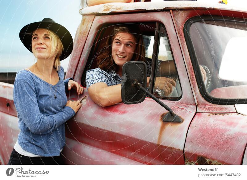 Lächelndes junges Paar mit einem alten Pickup Kleinlastwagen Pick Ups Transportfahrzeug Kleintransporter Transportfahrzeuge Pärchen Paare Partnerschaft lächeln