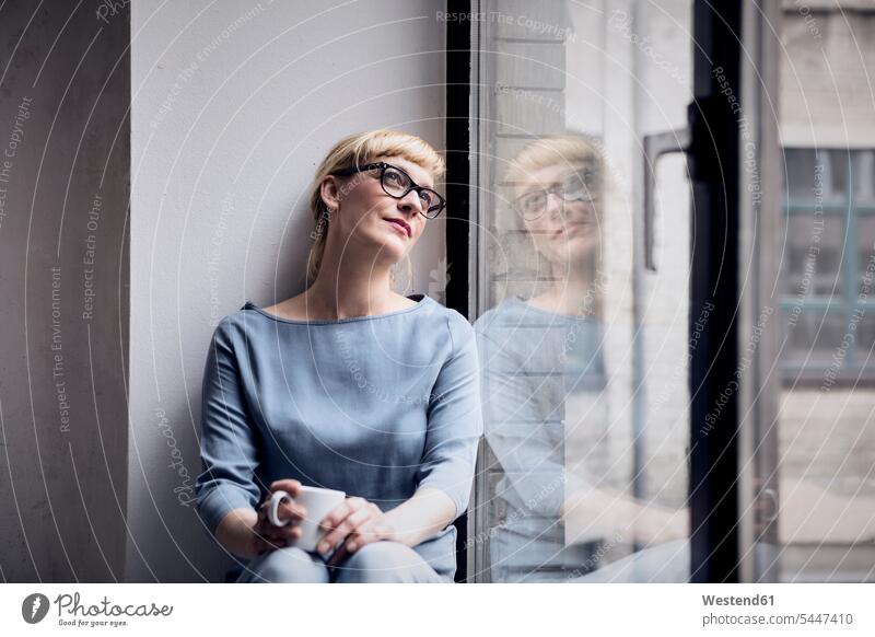 Porträt einer lächelnden Frau mit Kaffeetasse beim Blick durchs Fenster weiblich Frauen Portrait Porträts Portraits Erwachsener erwachsen Mensch Menschen Leute