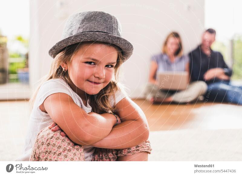 Kleines Mädchen mit Hut, Eltern mit Laptop im Hintergrund Hüte Zuversicht Zuversichtlich Selbstvertrauen selbstbewusst Vertrauen Drahtlose Technologie