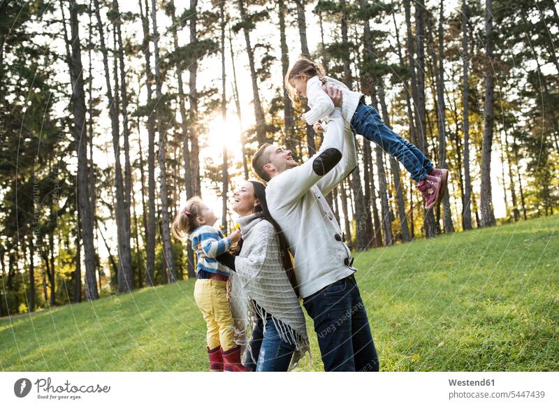 Verspielte Familie mit zwei Mädchen im Wald glücklich Glück glücklich sein glücklichsein Spaß Spass Späße spassig Spässe spaßig weiblich Familien lachen Kind