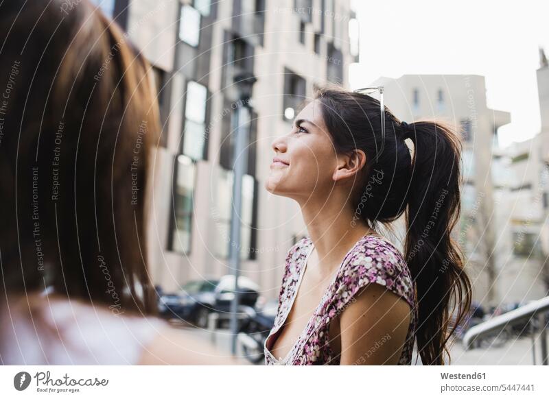 Lächelnde junge Frau in der Stadt schaut auf weiblich Frauen lächeln Erwachsener erwachsen Mensch Menschen Leute People Personen schön Ausschnitt Teil