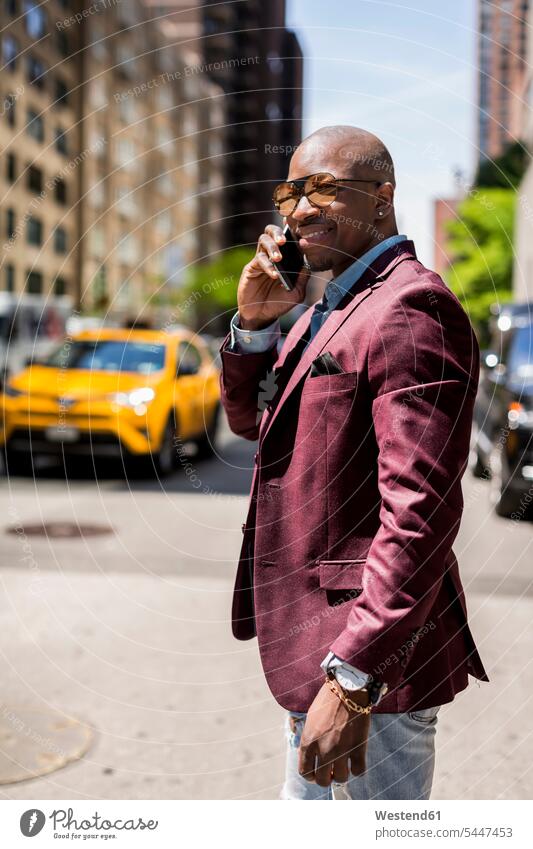 USA, New York City, Manhattan, Porträt eines lächelnden Geschäftsmannes am Telefon telefonieren anrufen Anruf telephonieren Businessmann Businessmänner