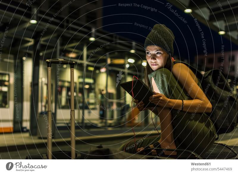 Porträt einer jungen Frau mit Kopfhörer und Tablette, die nachts am Bahnhof wartet weiblich Frauen Erwachsener erwachsen Mensch Menschen Leute People Personen