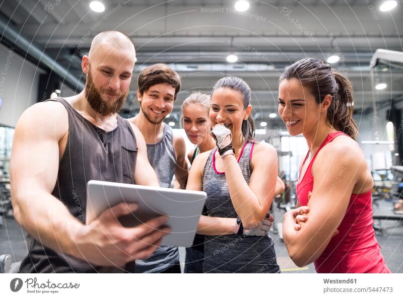 Gruppe glücklicher Sportler mit Tablette nach dem Training im Fitnessstudio Fitnessclubs Fitnessstudios Turnhalle ansehen lächeln Tablet Computer Tablet-PC