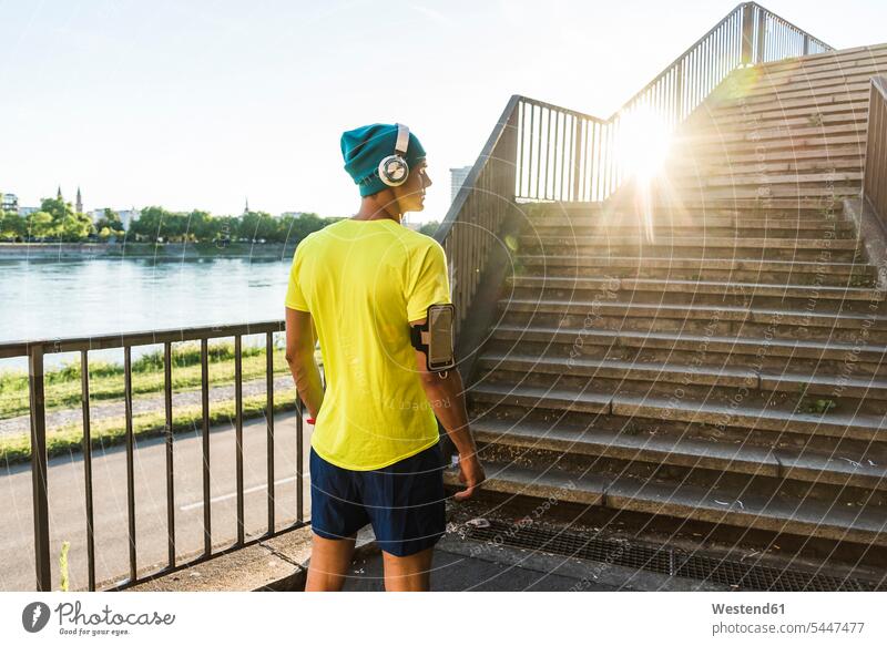 Junger Athlet joggt in der Stadt die Treppe hinauf Kopfhörer Kopfhoerer Treppenaufgang Brücke Bruecken Brücken Sportler fit laufen rennen Jogger sportlich Mann