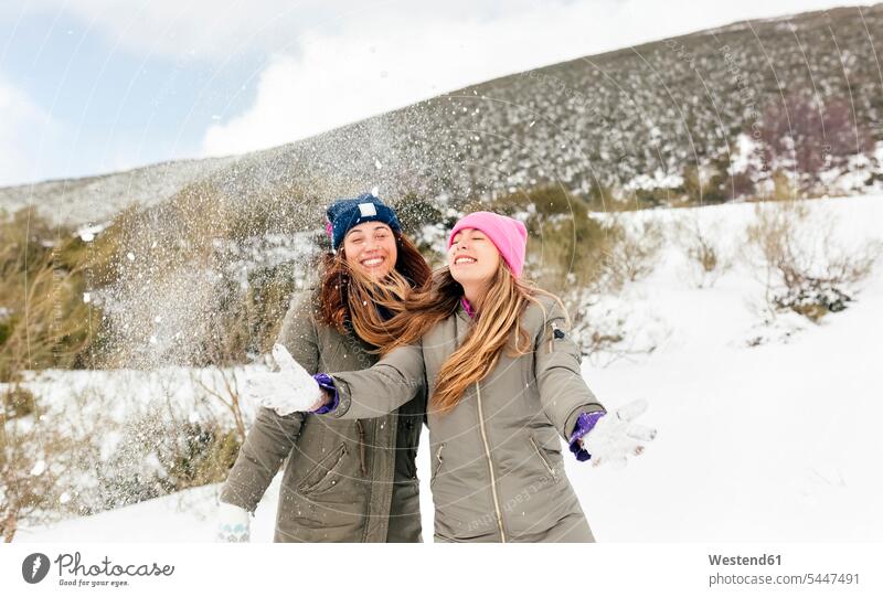 Zwei Freunde amüsieren sich im Schnee Freundschaft Kameradschaft Freundinnen werfen Wurf lachen Winter winterlich Winterzeit Wetter positiv Emotion Gefühl